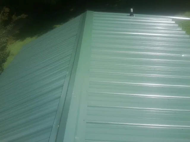 New green metal panels meeting at the ridge of a roof — Flat Roof Repair work by our crew in Rockwood