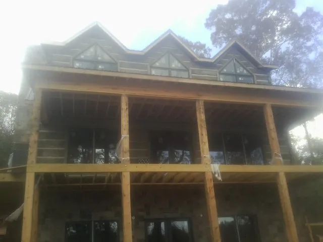 Dormers and porch framing on a large log home under construction — Roof Coating work by our crew in Rockwood