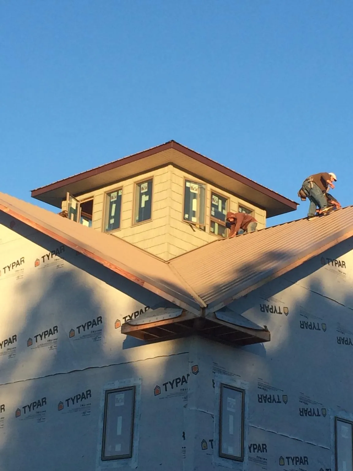 Roofers working around a rooftop cupola on a new metal roof at sunset — Roof Waterproofing in Rockwood by Roofing Brothers